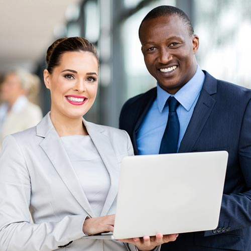 Business professionals smiling while holding a laptop